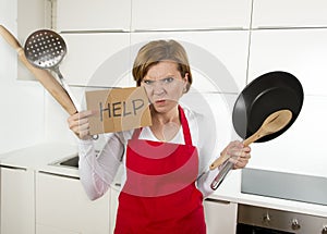 Home cook woman in red apron at domestic kitchen holding pan and household in stress