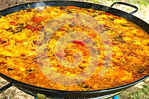 Home cooked Spanish Valencian paella in large flat frying pan. Variety of meats, vegetables, rice, tomato sauce. photo