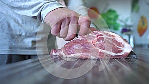 Home Cooking Food, Pork Meat. Man Cuts Pork Meat With Knife In Home Kitchen. Man's Hand Holds a Knife. Chef Cutting Meat