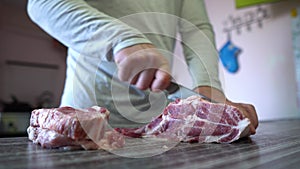 Home Cooking Food, Pork Meat. Man Cuts Pork Meat With Knife In Home Kitchen. Man's Hand Holds a Knife. Chef Cutting Meat