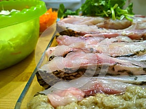 Home cooking. Pieces of fresh raw fish fillet bream with herbs. Preparing healthy food in home kitchen. Food ingredients. Recipe f