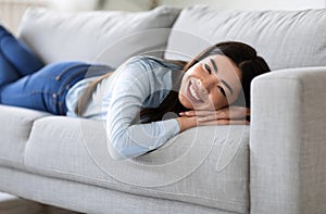 Home Cosiness. Relaxed Asian Girl Lying On Comfortable Sofa In Living Room