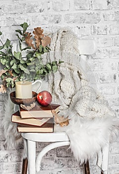 Home cozy still life - an old vintage chair, stack of books, knitted plaid, candle, apple fruit. Hobby, leisure, comfort concept.