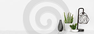 Home decor banner with lamp, vase and plants against a white shelf and wall with copy space