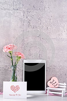 Home decor with blooming carnation and tablet as photo frame beside wall on the table - Close up, copy space, mock up, beautiful