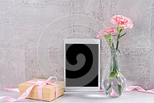 Home decor with blooming carnation and tablet as photo frame beside wall on the table - Close up, copy space, mock up, beautiful