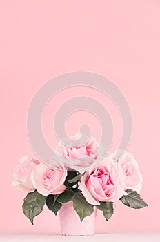 Home decor with flowers in romantic style - pastel pink roses bouquet in basket on white wood table, copy space.