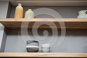 Home decor - various neutral colored vases wooden shelf against grey wall.