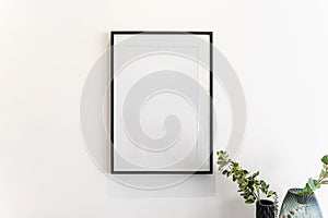 Home decoration, empty black frame, poster, white canvas, mock up on a white wall, living room, template