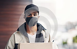 The home delivery business is booming. a masked young man delivering a package to a place of residence.