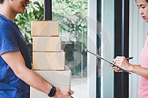 Home delivery service and working with service mind, Woman customer signing and receiving a cardboard boxes parcel from