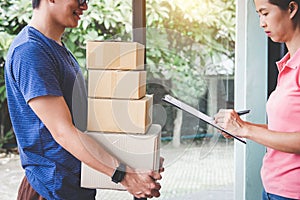 Home delivery service and working with service mind, Woman customer signing and receiving a cardboard boxes parcel from