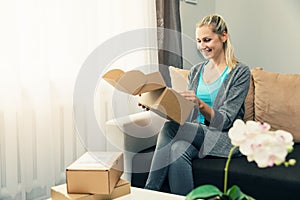 Home delivery - smiling young woman opening cardboard box