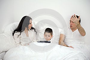 home disagreements parents quarrel in bed under covers son boy with tablet psychological problems conflicts