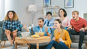 At Home Diverse Group Friends Watching TV Together, Eating Snacks and Drinking Beverage. They Prob