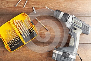 home DIY repair concept image with a hand held drill and a set of drill bits as well as two screws and a peg