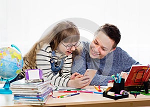 Home education, distance learning, home lessons. Sister and brother do their homework at home. The girl use her smartphone