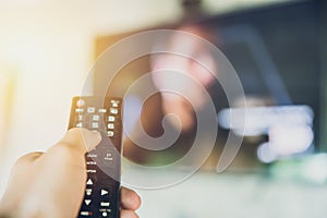 Home entertainment. hand hold Smart TV remote control with a television blur background