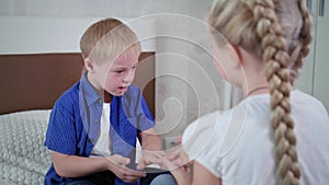 Home entertainment, little boy with down syndrome and girl playing rock paper scissors sitting on bed in room