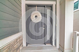 Home entrance with festive wreath on the gray front door with narrow sidelight