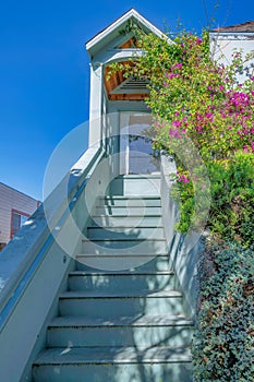 Home entrance with stairs near shrubs leading to a porched with picture windows at San Francisco, CA