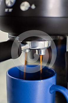 Home espresso machine pouring fresh coffee in blue mug