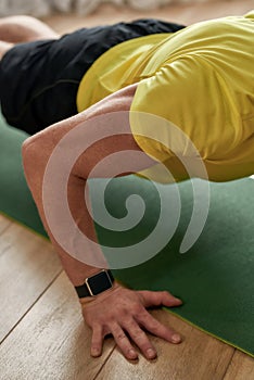 Home exercises. Cropped shot of a strong man fitness instructor in sportswear doing push ups on yoga mat at home