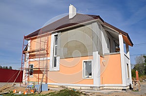 Home exterior renovation and outside house walls painting. A close-up of a house under renovation with scaffolding for rendering,