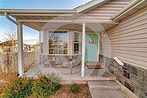Home facade featuring open concrete porch bay window and pastel green door