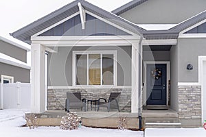 Home facade with gable roof front porch and door with wreath in winter