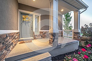 Home facade with pillars and railing on the porch and wreath on the gray door