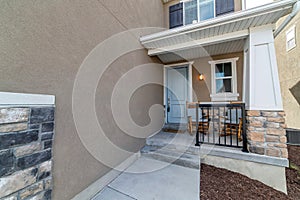 Home facade with rocking chairs at the small front porch with railing and steps