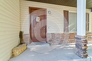 Home facade with white siding and stone bricks wall and concreate front porch