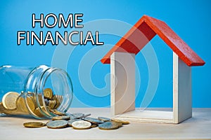 Home Financial Conceptual. Model of house and coins on the wooden table with blue background.