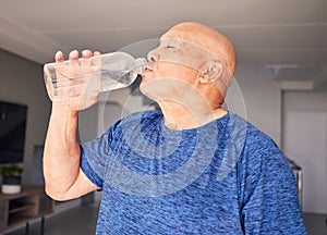 Home, fitness or senior man drinking water for wellness, hydration or exercise recovery in retirement. Training, fatigue