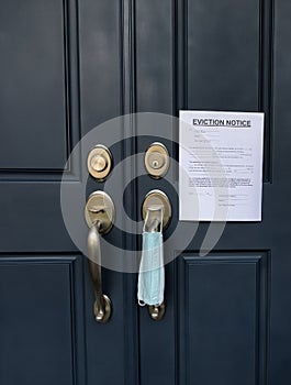 Home front door with eviction notice and facemask for renter in default during coronavirus pandemic