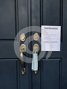 Home front door with eviction notice and facemask for renter in default during coronavirus pandemic photo