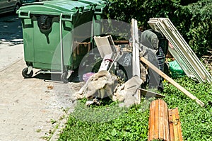 Home furniture wardrobe and windows thrown in the garbage on the street in the city near plastic dumpster cans littering and pollu