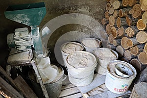 Home grain mill, ground animal feed in buckets, stacked firewood in shed