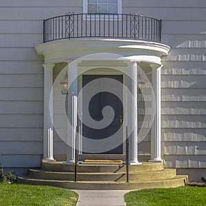 Home with gray door columns balcony and stairs