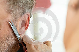 Home hairdresser cutting mans hair at indoors. Wife cutting husbands hair during quarantine