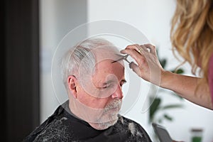 Home hairdressing concept, senior man the hair cutting by woman hairdresser