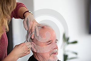 Home hairdressing concept, senior man the hair cutting by woman hairdresser