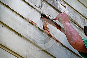 A home handyman has found some rot in a weatherbord on the house. He is testing it with a screwdriver to see how deep it goes