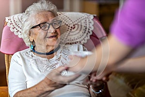 Home healthcare nurse gives a senior female a cup of hot tea