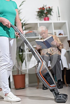 Home helper vacuuming for an old woman