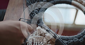 Home hobby, knitting macrame. Women's hands knit an ornament with thick threads.