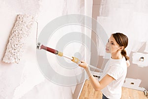 Home improvement. Beautiful woman painting wall with paint roller.