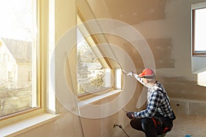 Home improvement handyman filling drywall with filler in new build attic