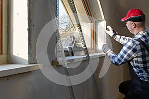 Home improvement handyman installing window in new build attic by using leveler and laser leveler